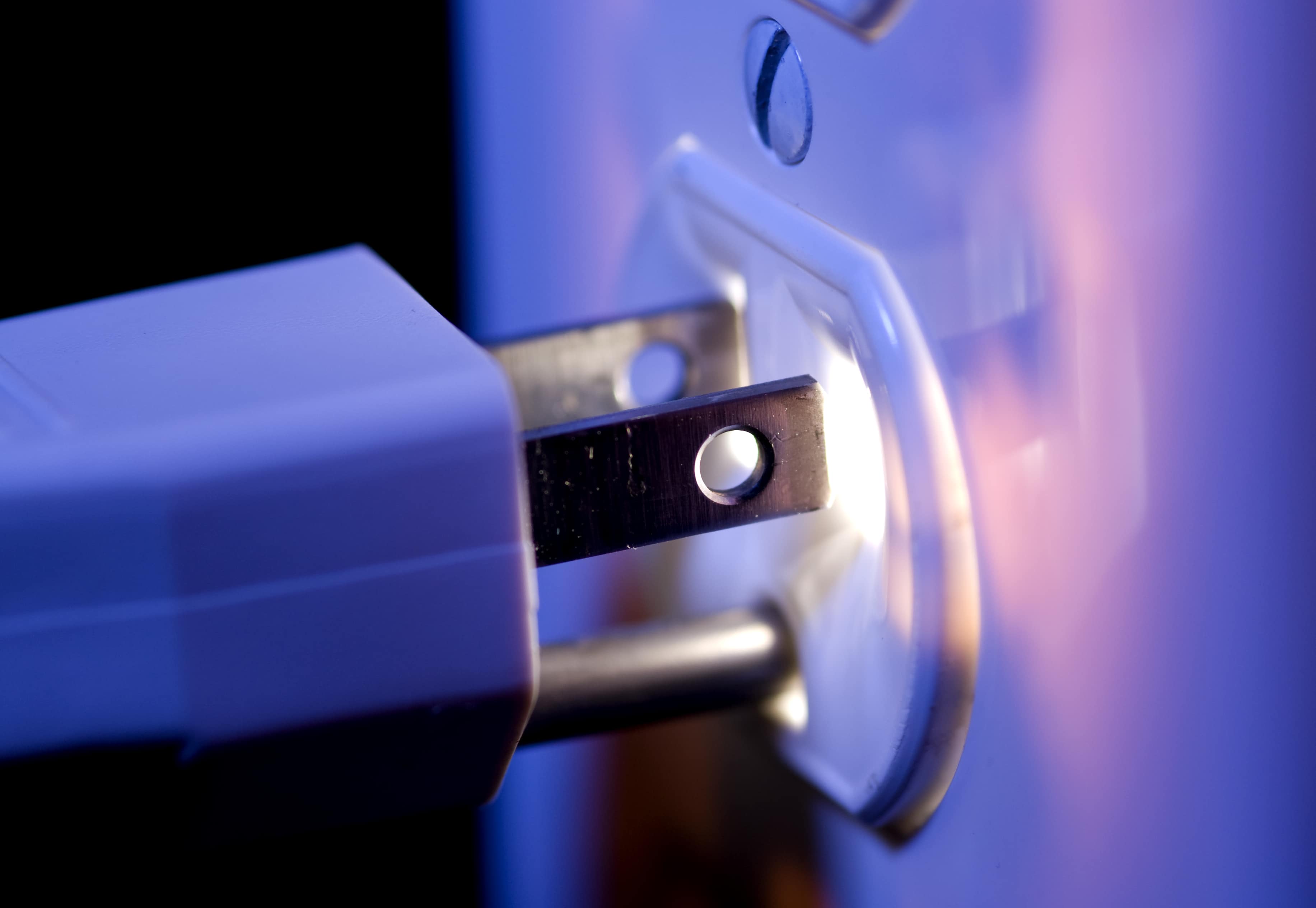 An electric outlet glowing from within and a three prong electric plug and cord.