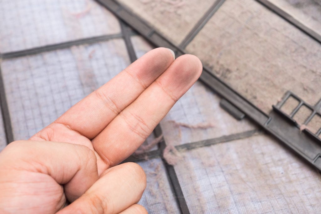 Dirty air conditioner filter and dirty finger.