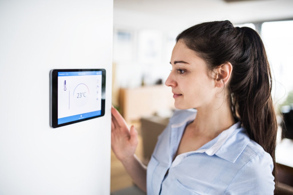 A woman looking at tablet with smart home control system.