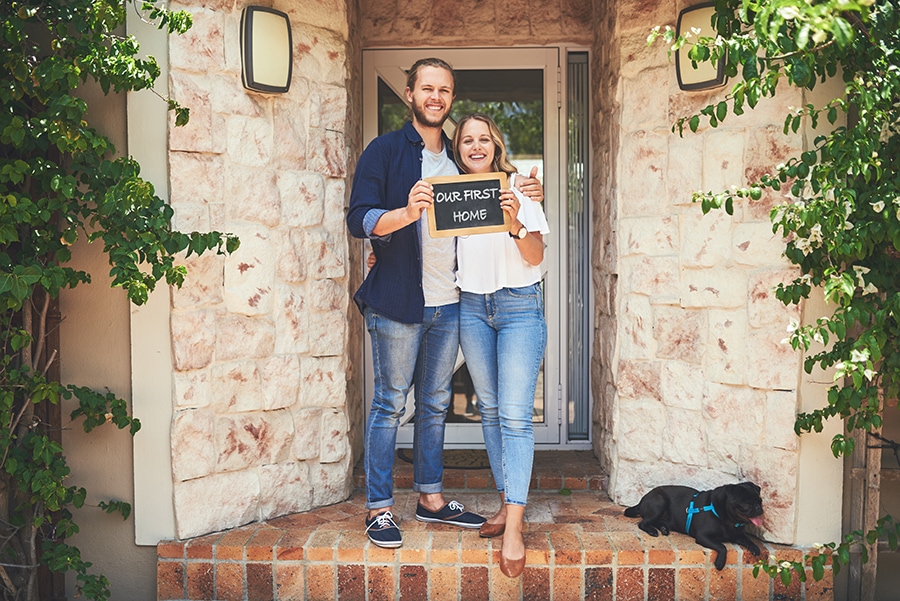 first time homebuyers in front of their new home.