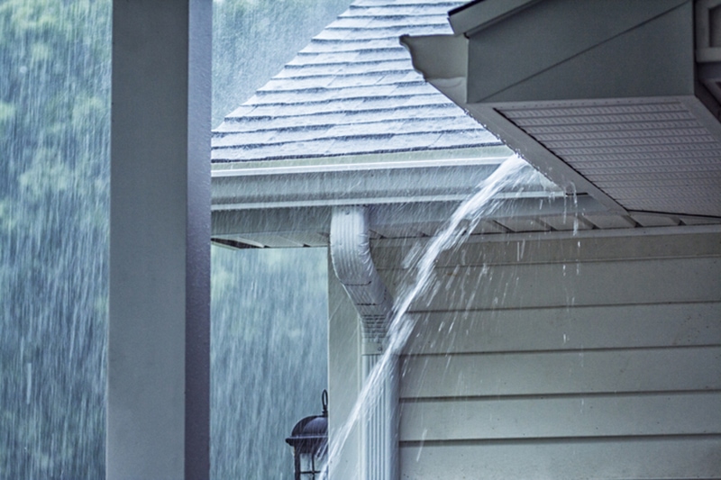 Water pouring from the clogged gutters of a home | How to Protect Your AC or Heat Pump From Storms | Clinton Township, MI