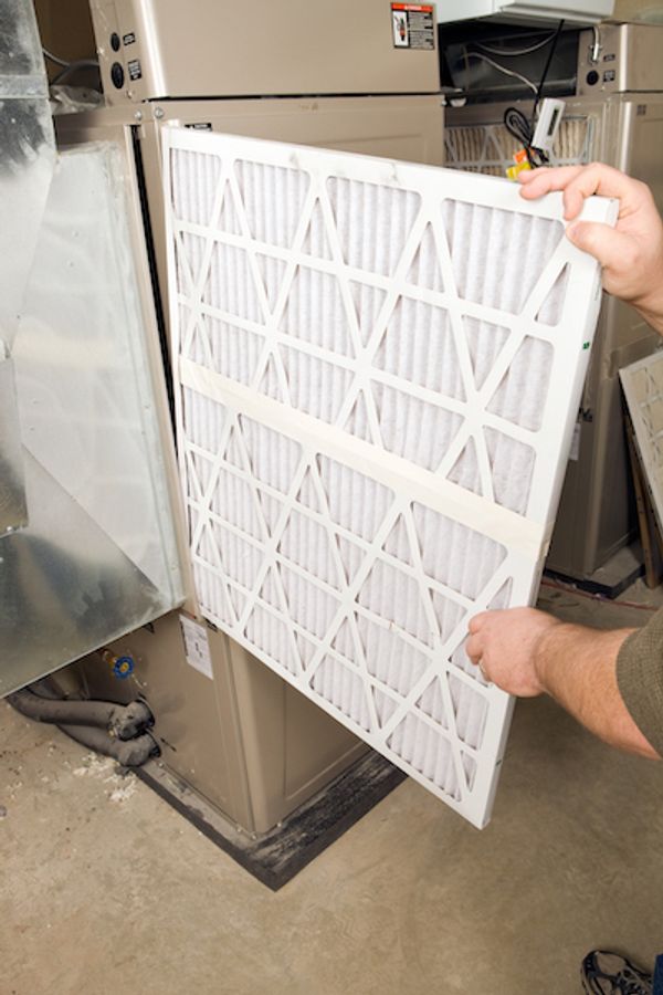 Image of someone replacing filter in furnace. When Is the Best Time for a Furnace Tune-Up?