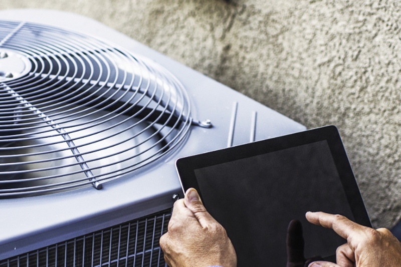 Maintenance engineer using digital tablet to inspect air conditioning unit.