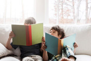 Shot of two adorable brothers reading books while relaxing together on the sofa at home.