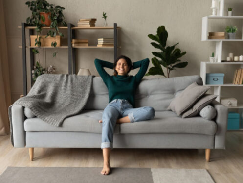 How a Whole-House Humidifier Keeps You Healthy. A woman relaxing on her couch breathing in clean air.