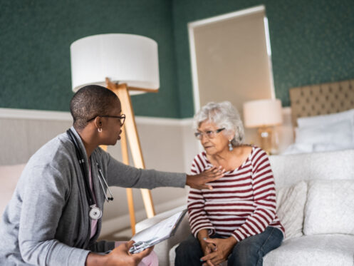How Your HVAC Equipment Protects Against Viruses. Doctor talking to a senior woman in the bedroom.